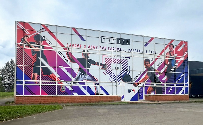 Transforming a 1980s sports complex façade with vibrant printed graphics. Transforming a 1980s sports complex façade with vibrant printed graphics.